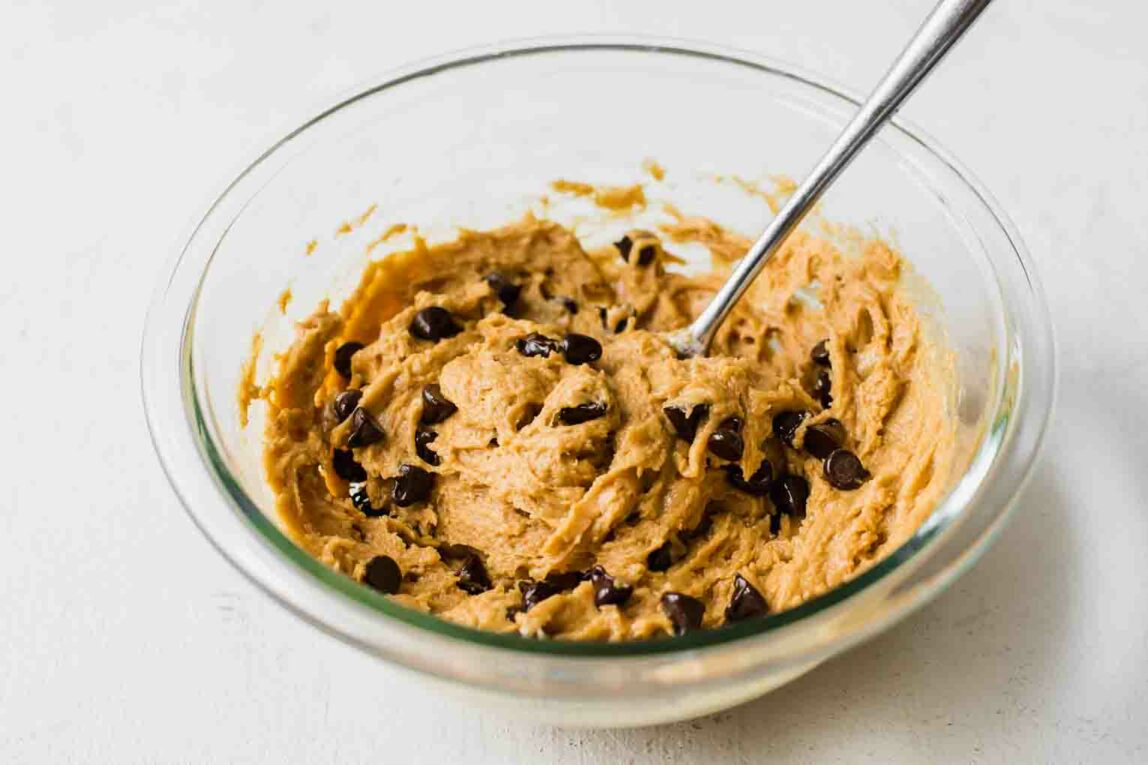 Protein cookie dough being mixed in a glass bowl.