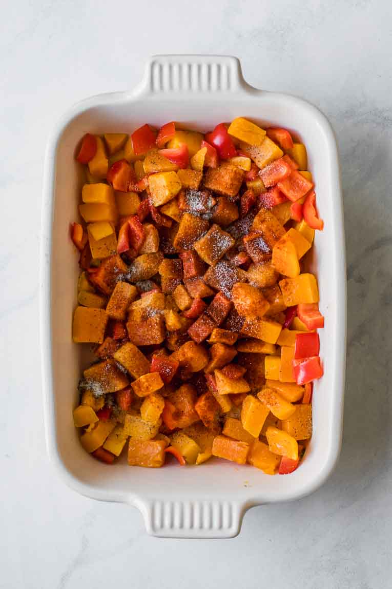 Seasoning added to butternut squash in a casserole dish.