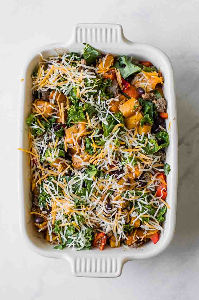 Uncooked butternut squash casserole topped with cheese.