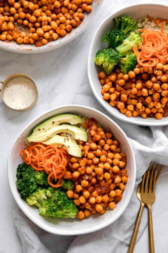 Two chickpea bowls with vegan buffalo sauce on a marble countertop.