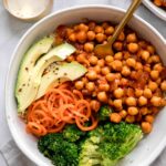 Close up of vegan buffalo chickpea bowls with a fork on a marble background.