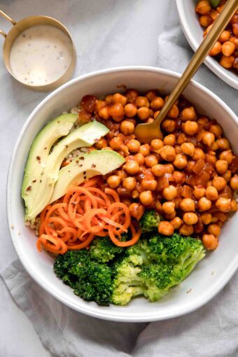 Close up of vegan buffalo chickpea bowls with a fork on a marble background.