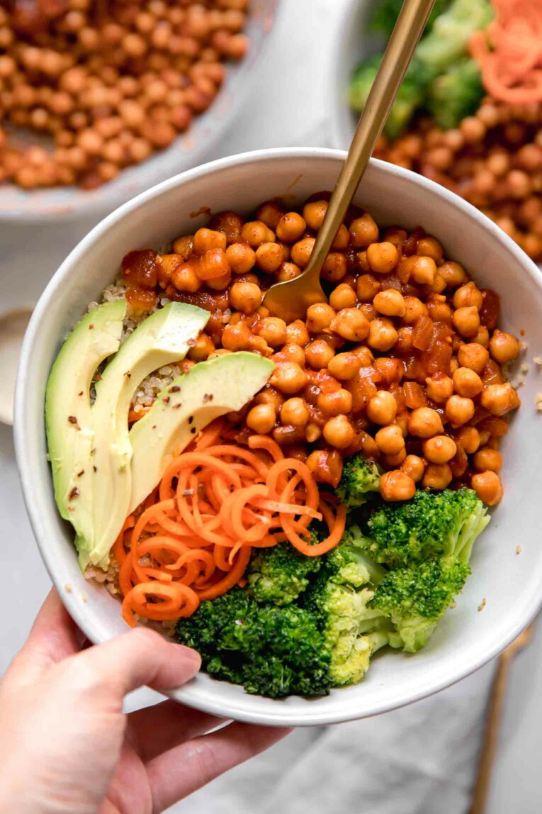 Hand holding buffalo chickpea grain bowl.