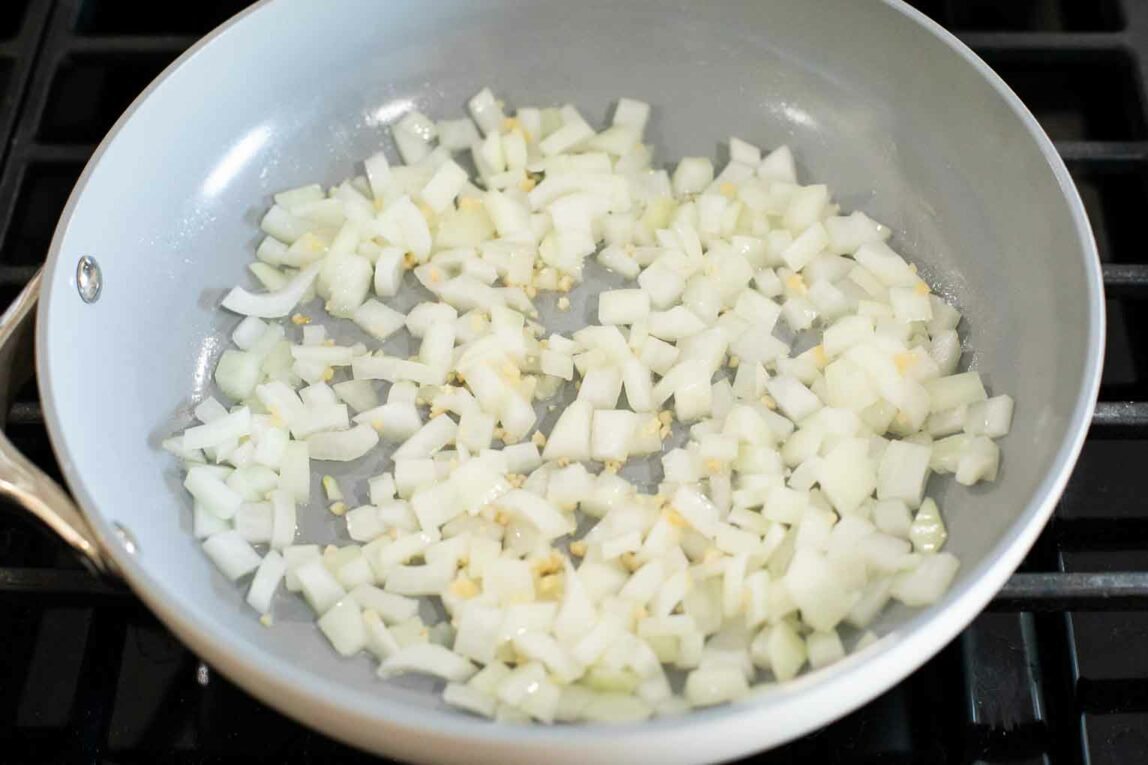 Onions and garlic being cooked in a pan.