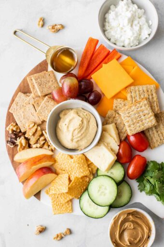 Better-for-you snack ideas on a white marble round cheeseboard.