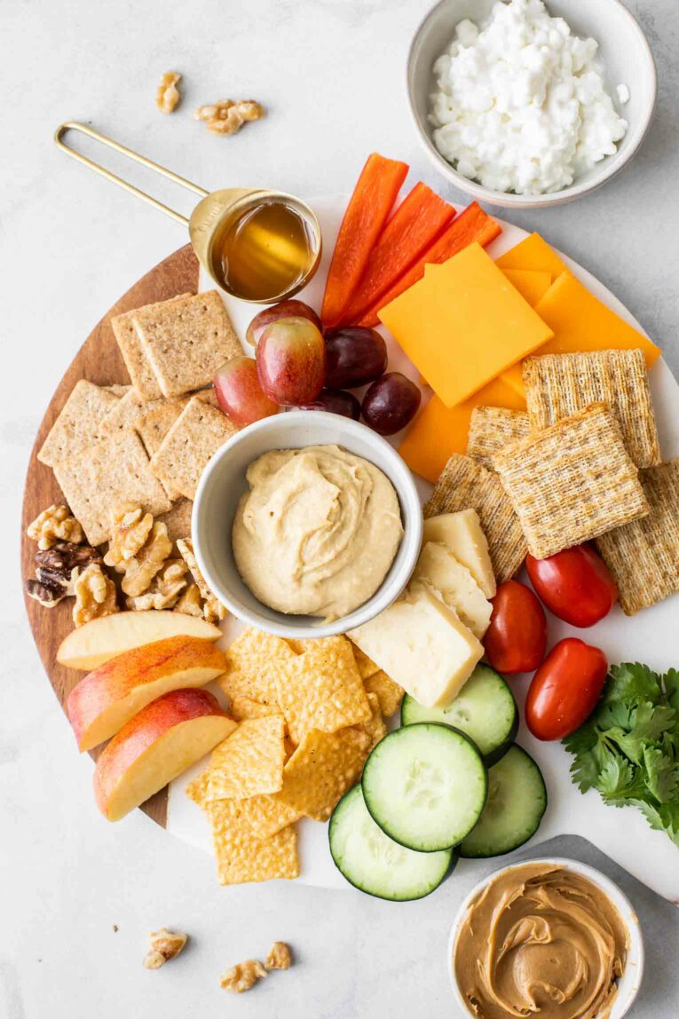 Better-for-you snack ideas on a white marble round cheeseboard.