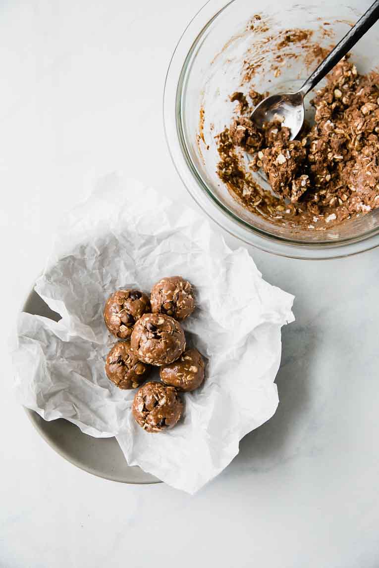 Mixing bowl with mixture for protein balls alongside bowl of formed balls.