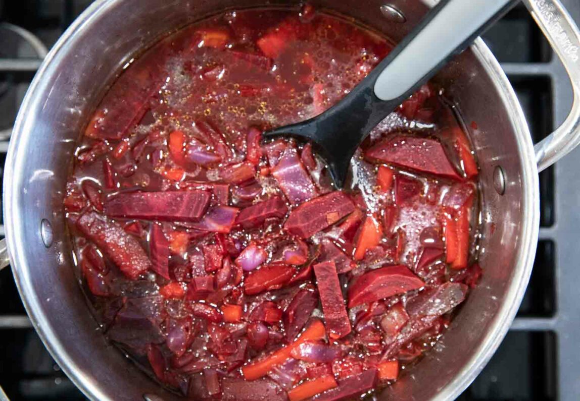 Cut up beets in a pot over a stove.