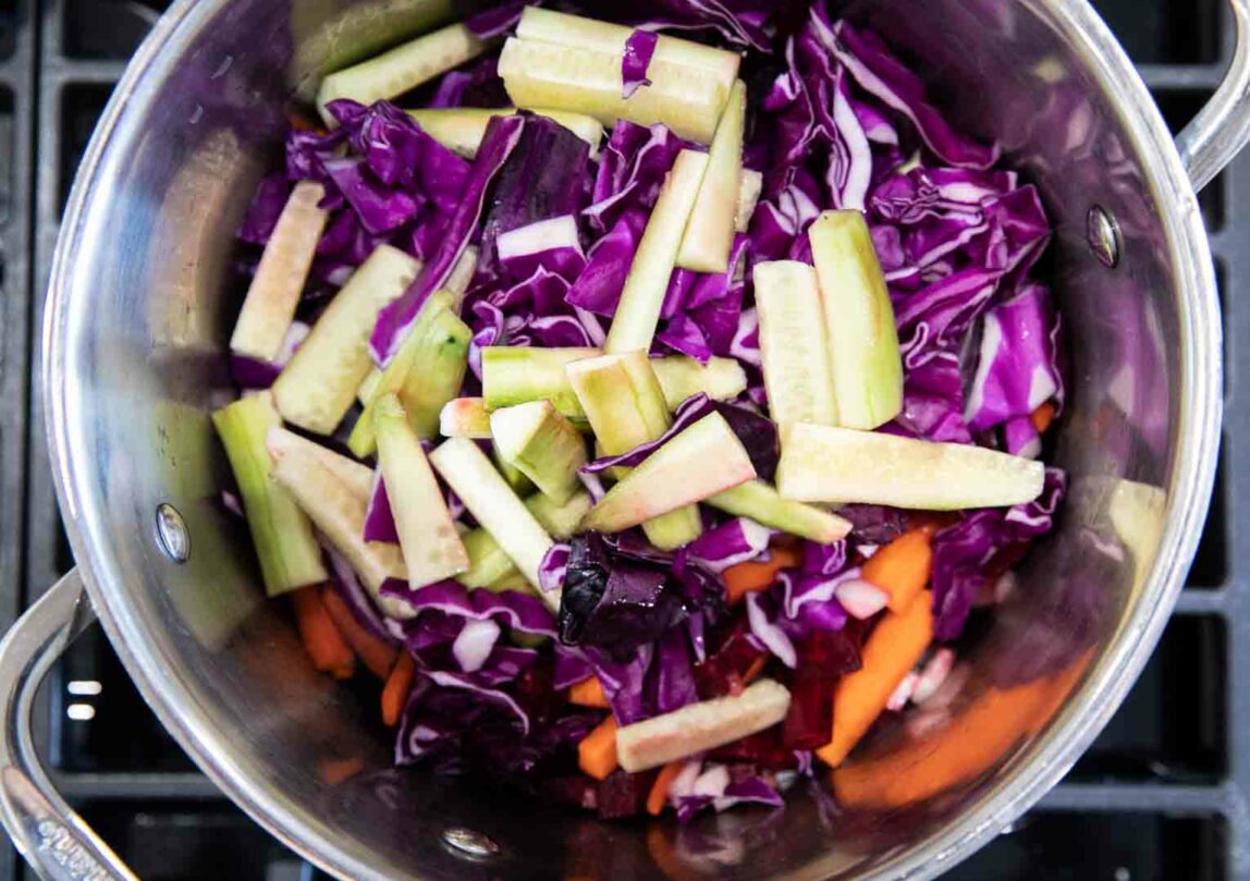 Vegetables in a pot being cooked over a stove.