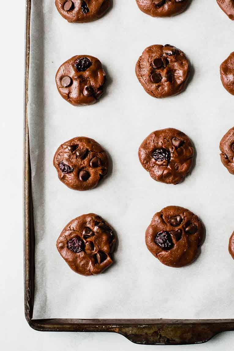 Chocolate cherry cookie dough on a baking sheet with parchment paper.
