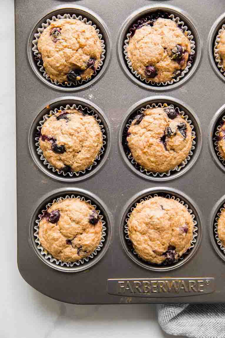 Freshly baked blueberry muffins in a lined muffin tin.