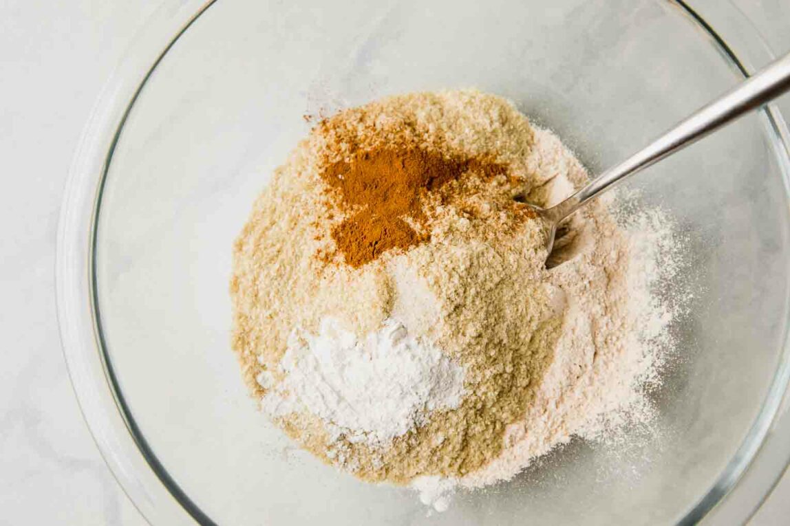 Dry ingredients for muffins being mixed in a glass bowl.
