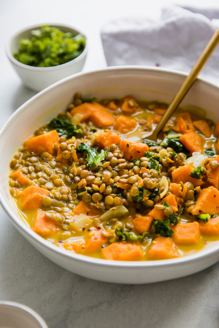 Angled shot of Vegetarian Lentil & Sweet Potato Curry Stew in a white bowl.
