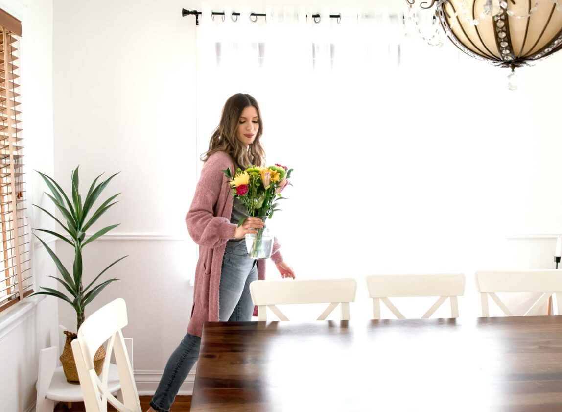 Woman adding flowers to her table to refresh home for spring.
