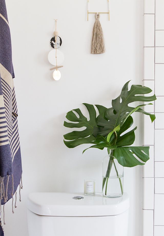 A plant in a vase a top a small toilet. 