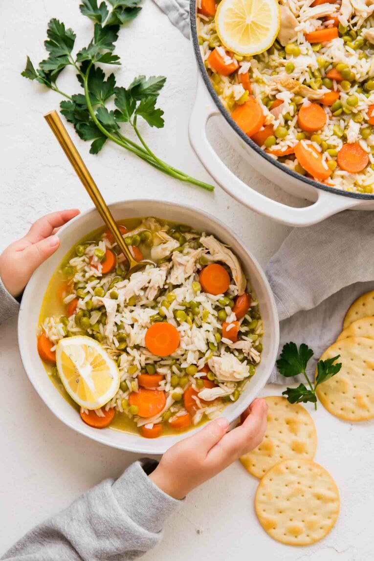 Hands holding bowl of Chicken Lemon Rice Soup.