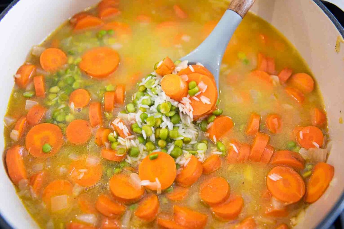 Lentils with broth added to carrots and onions in a dutch oven.