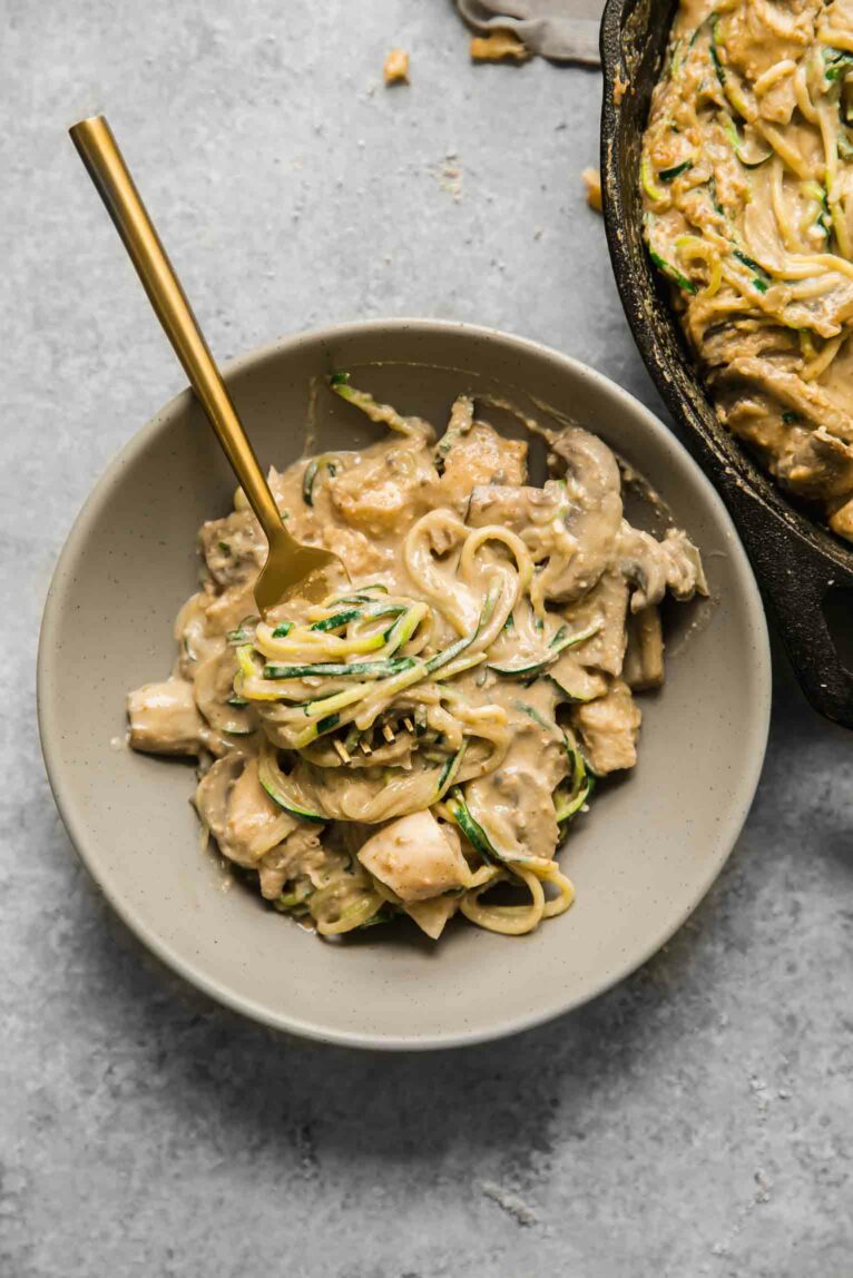 A bowl with chicken casserole and a gold spoon.