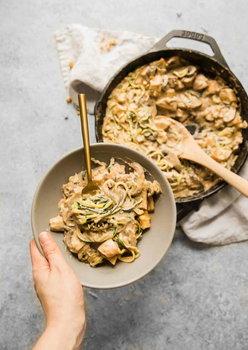 Hand holding a bowl of casserole.