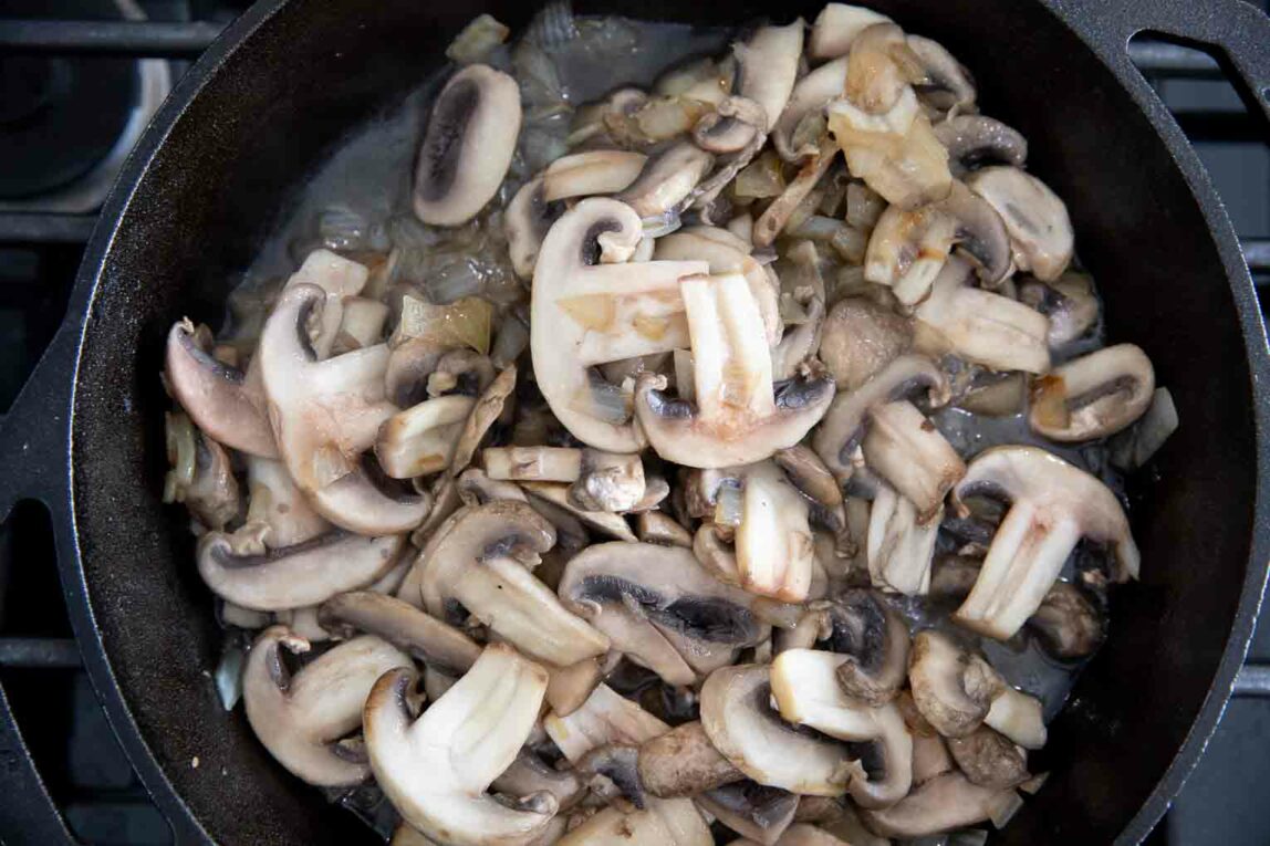 Mushrooms being sautéed in a cast iron skillet. 
