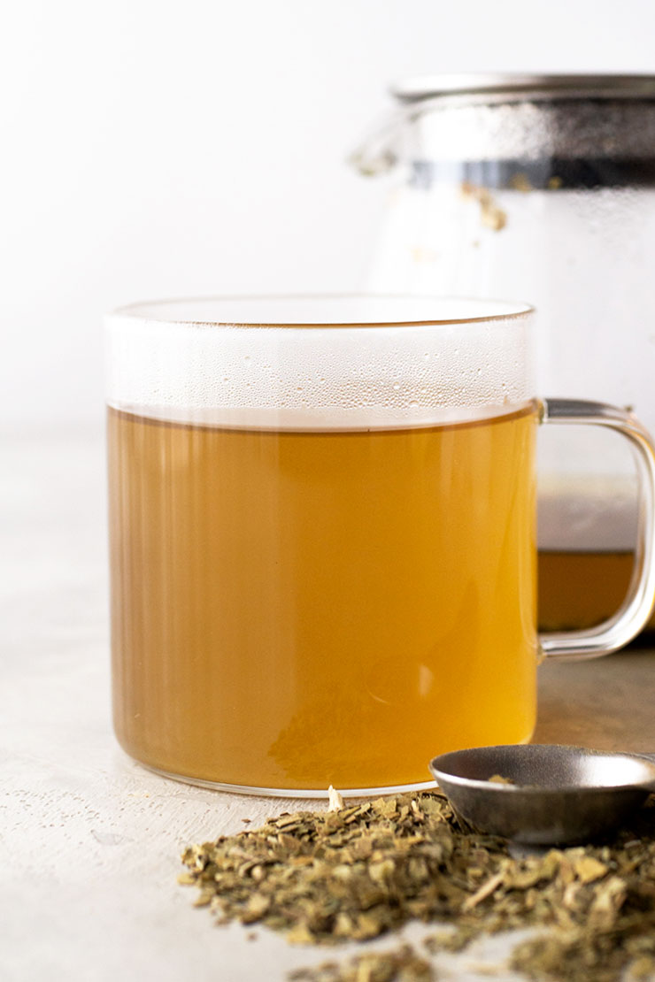 A photo of yerba mate drink in a clear glass mug.