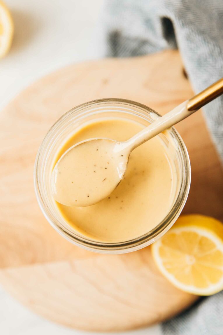 Spoon lifting tahini dressing out of mason jar.