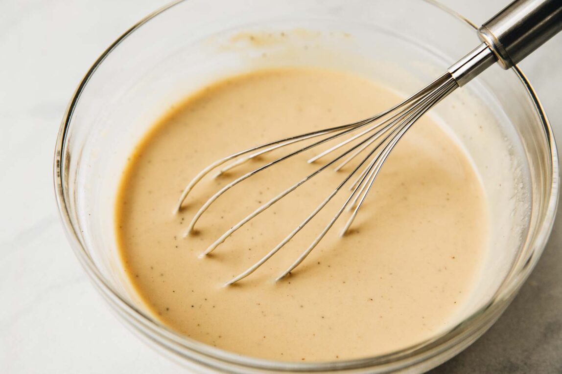 Lemon tahini dressing being whisked together in a bowl.