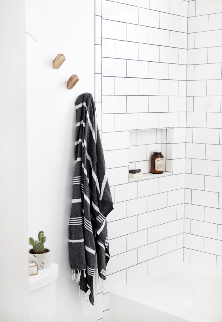 A small bathroom with gold hooks and a towel hanging.