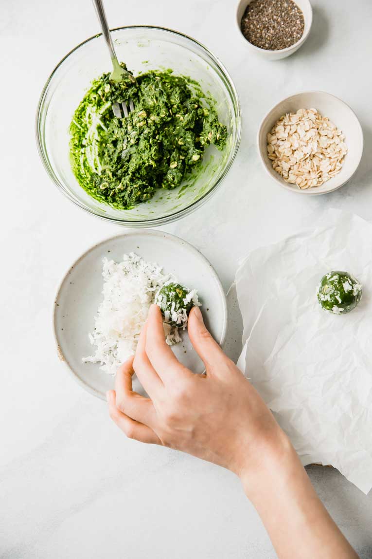 Rolling chia seed energy ball in coconut shreds.