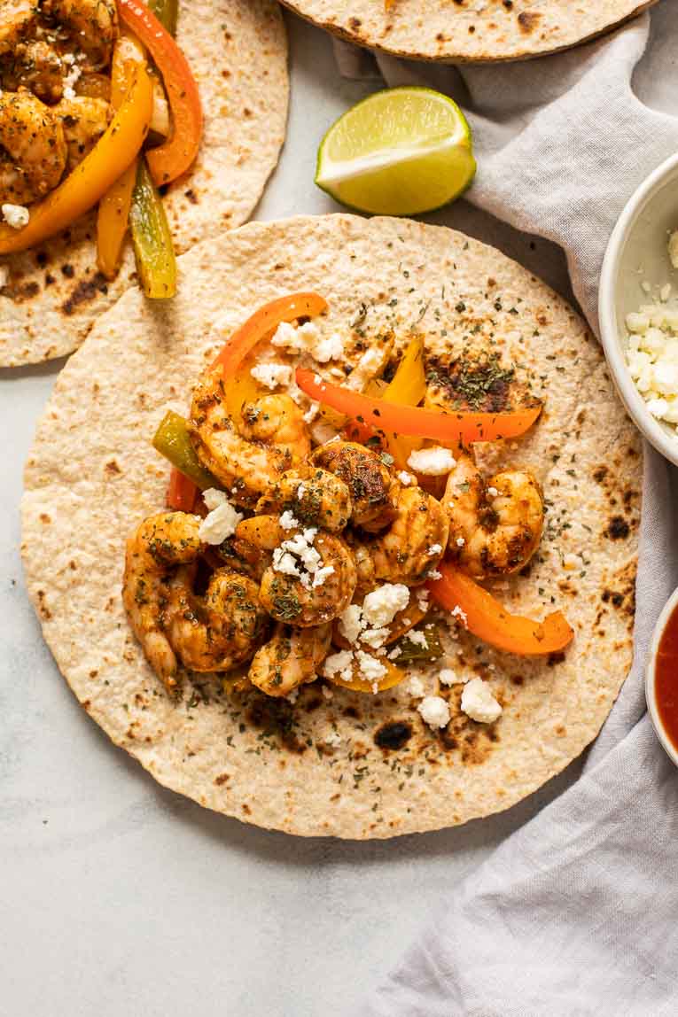 Close up of tortilla with shrimp and fajita vegetables.
