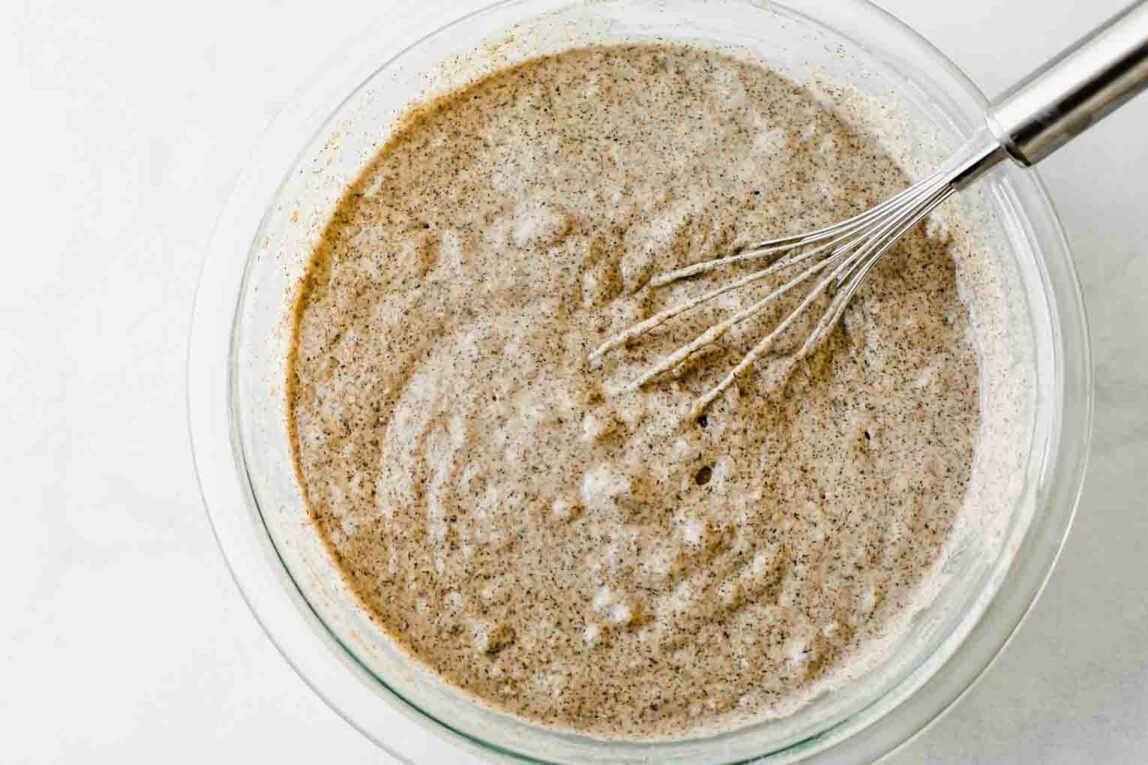 A mixing bowl with wet and dry ingredients being mixed in.