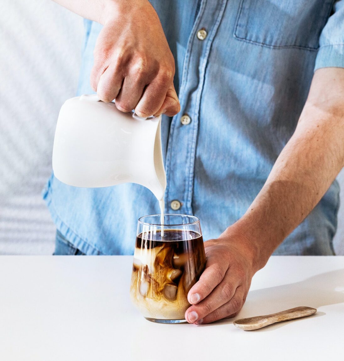 A barista pouring milk into a coffee drink. 