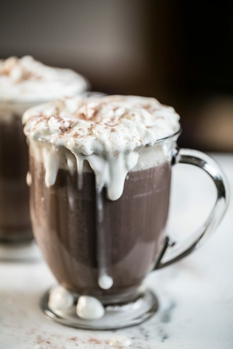 Two mugs of hot chocolate with whipped topping.