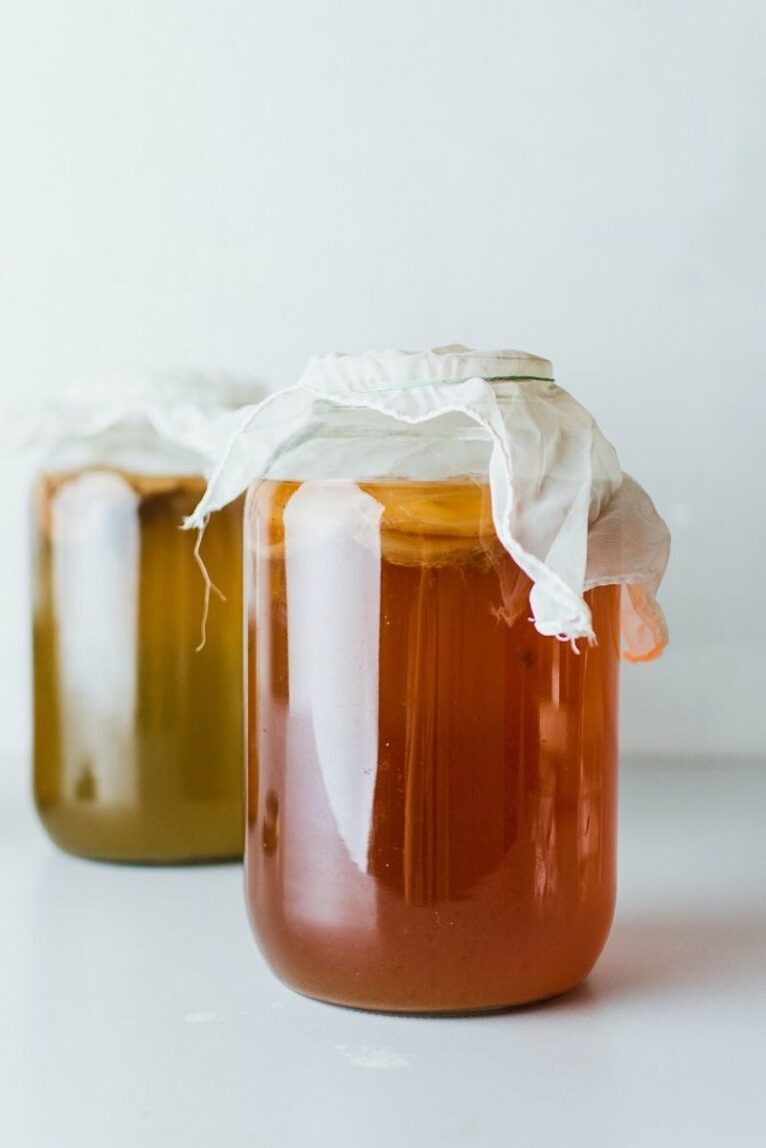 Two jars of kombucha with cheesecloth over them. 
