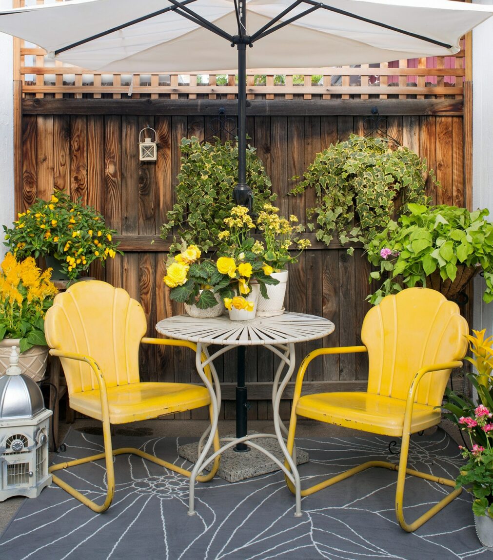 A small set of yellow patio chairs with a small table in between.