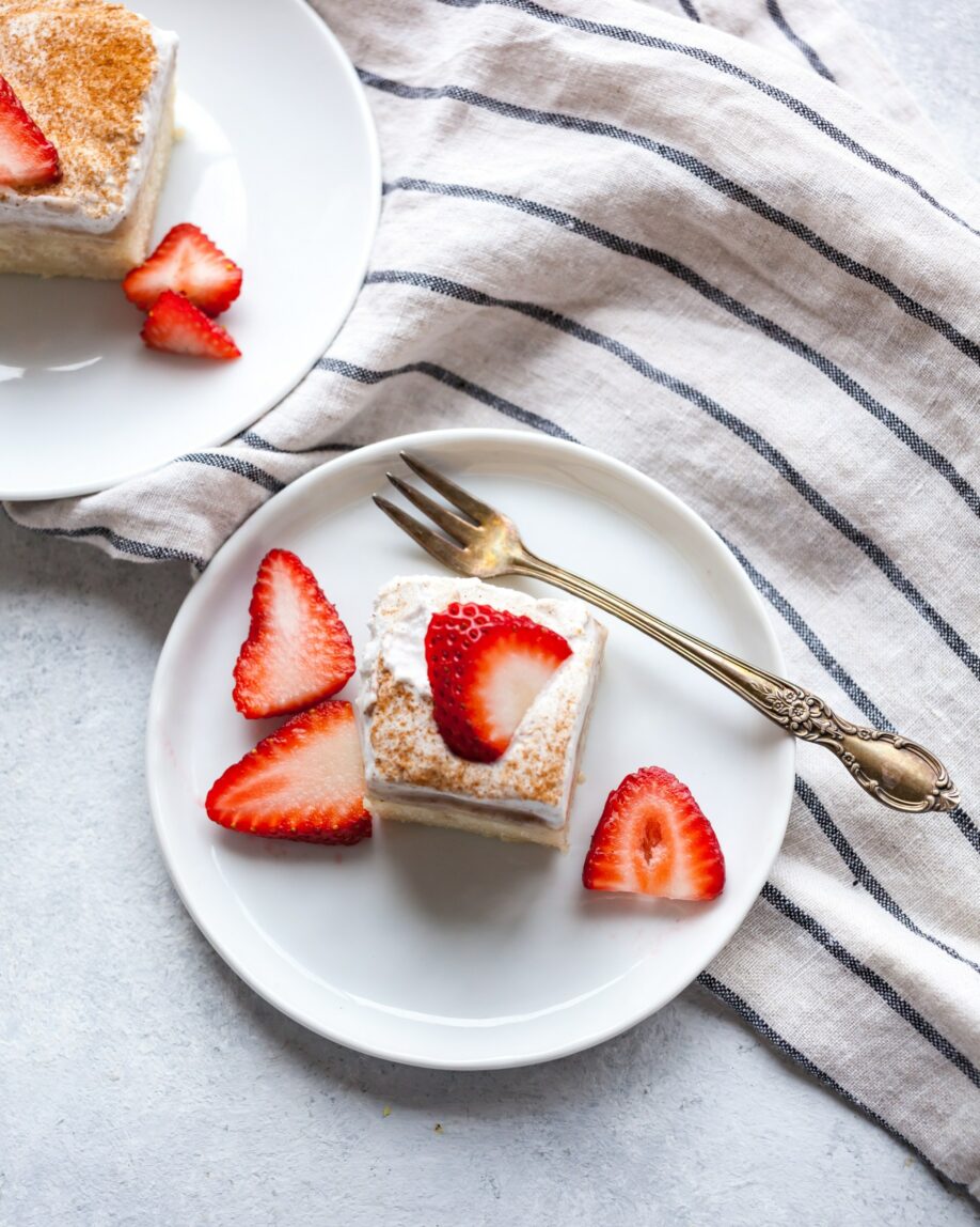A top shot photo of a tres leches cake with strawberries atop.