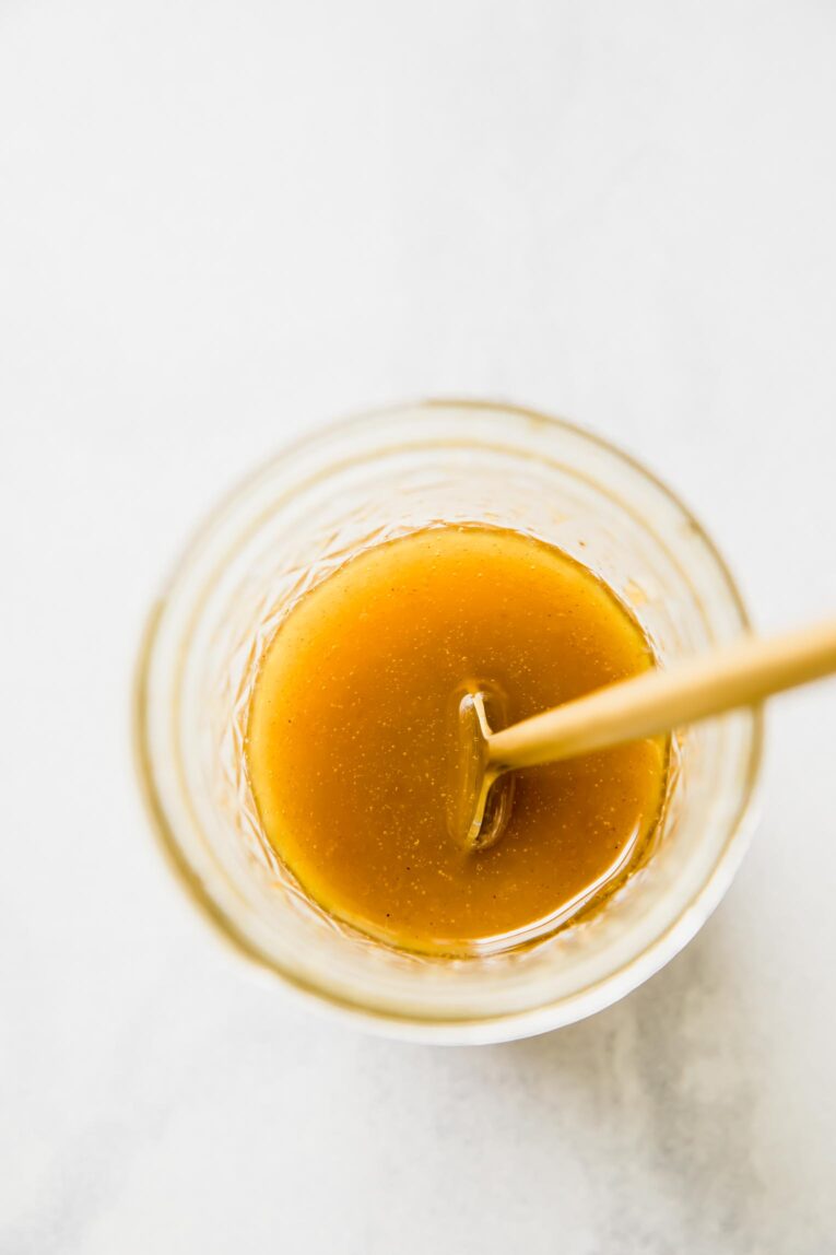 A top shot of a glass filled with the carrot salad dressing.