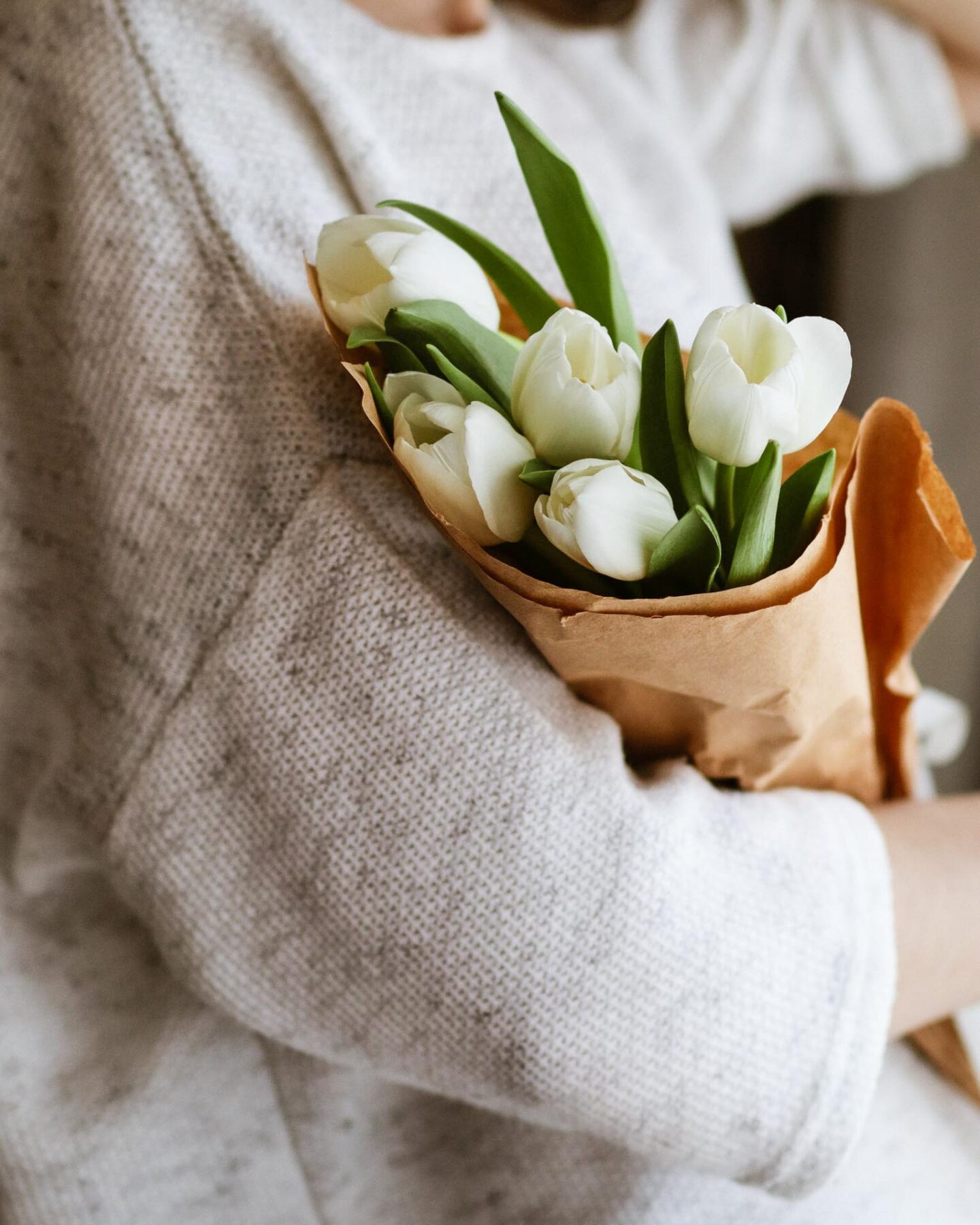 Mother in a white sweater holding flowers.