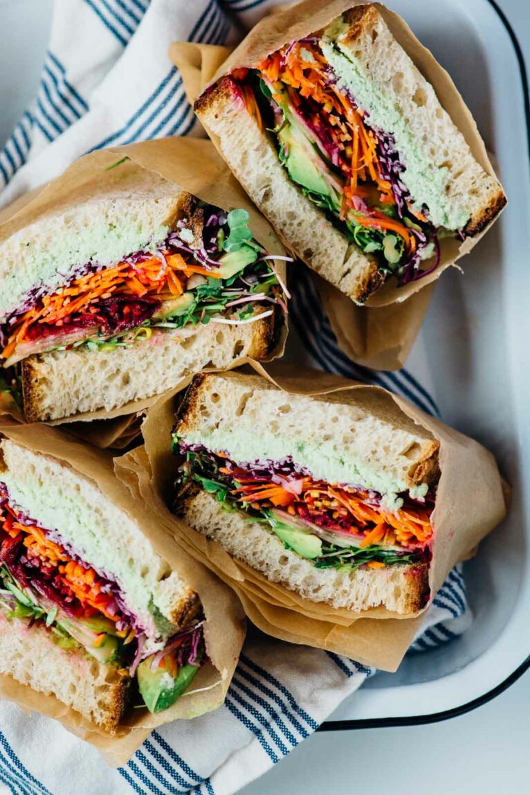 A photo of cut up rainbow veggie sandwiches wrapped in parchment paper.
