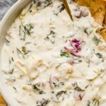 Close up of creamy spinach artichoke dip in a large bowl for a crowd.