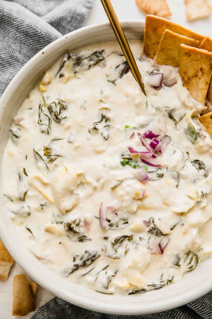 Close up of creamy spinach artichoke dip in a large bowl for a crowd.