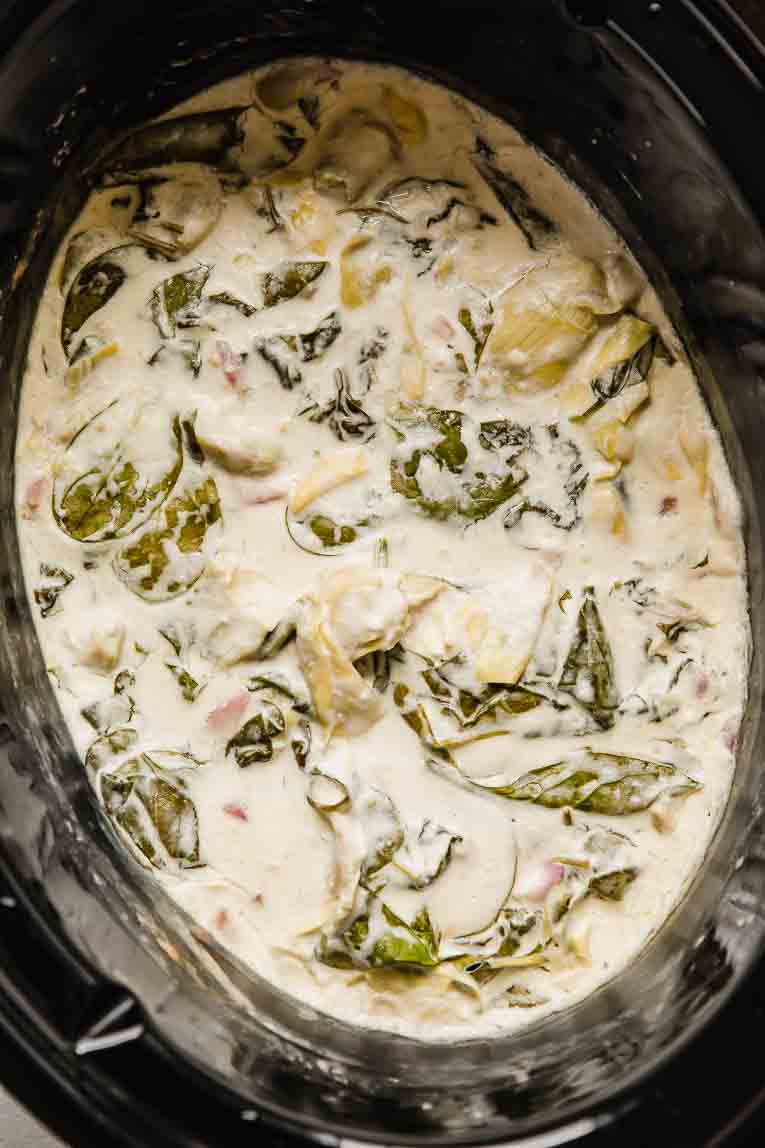 Top shot of spinach artichoke dip in a slow cooker.