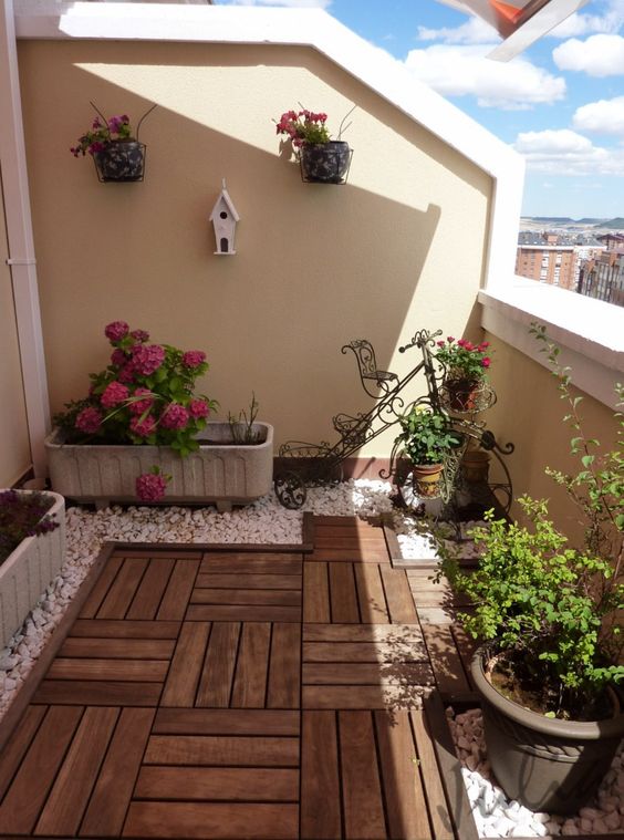 A small balcony with wood tiles and gravel rocks.