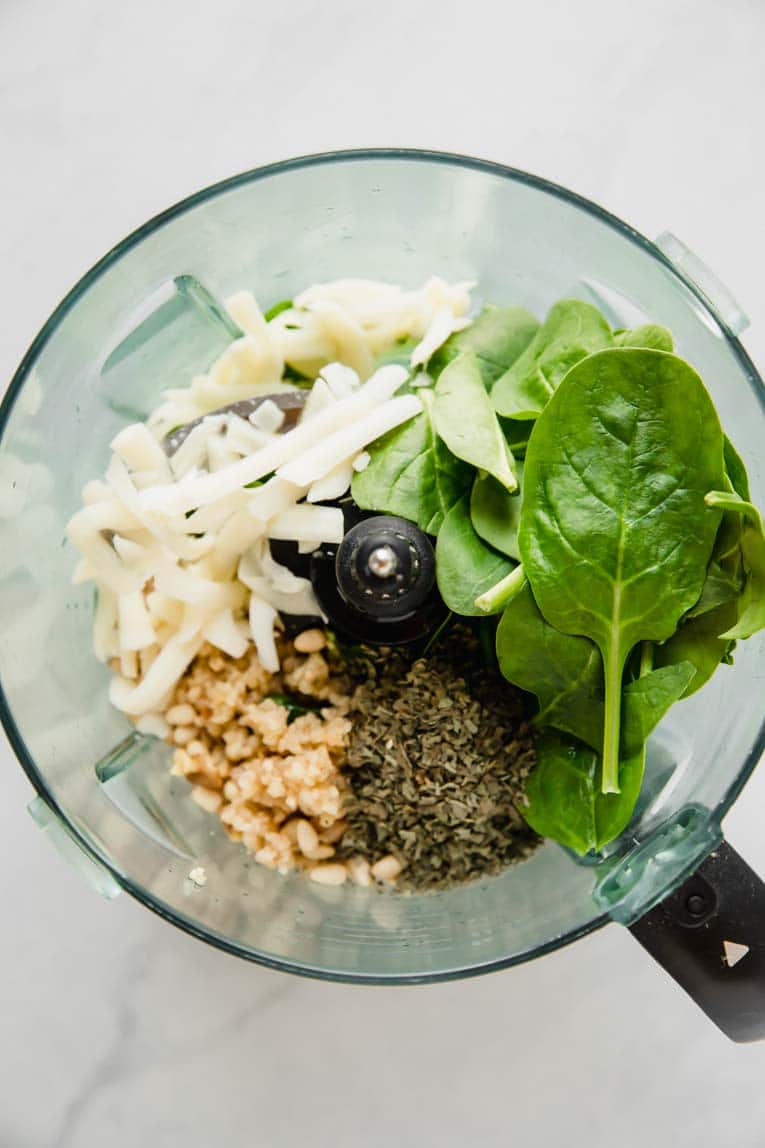 All the ingredients to make pesto sauce in a blender.