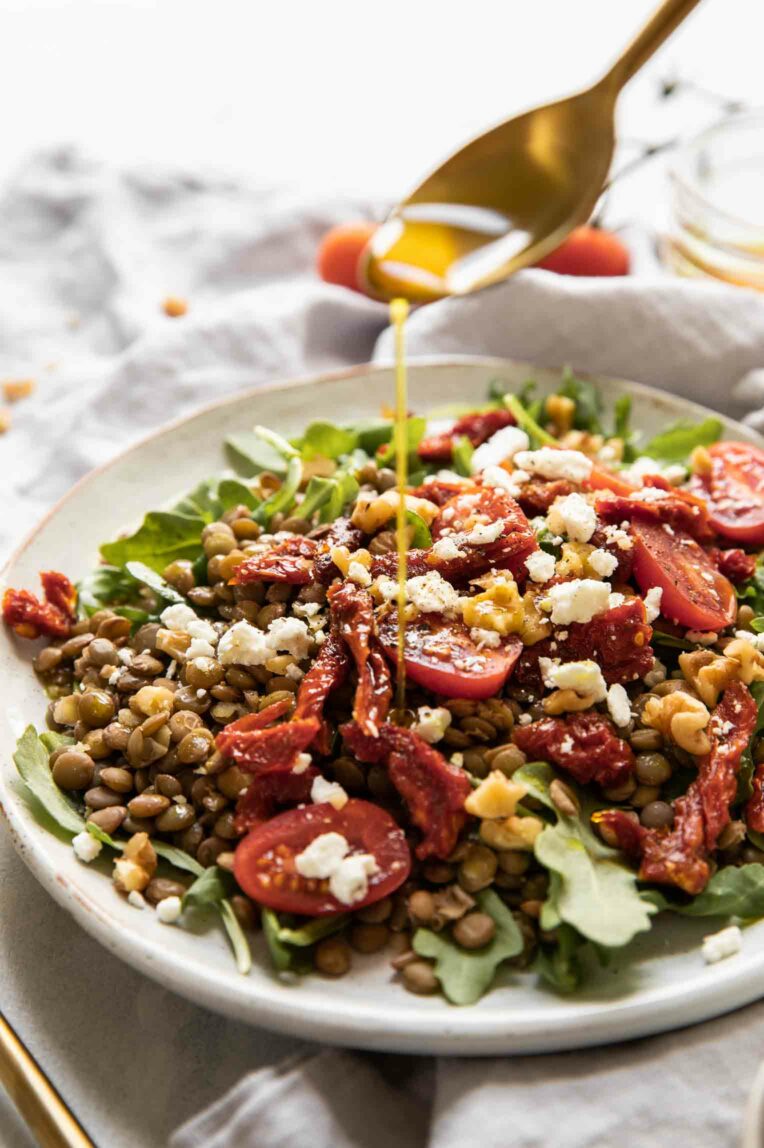 Vinaigrette being drizzled over lentil arugula salad.