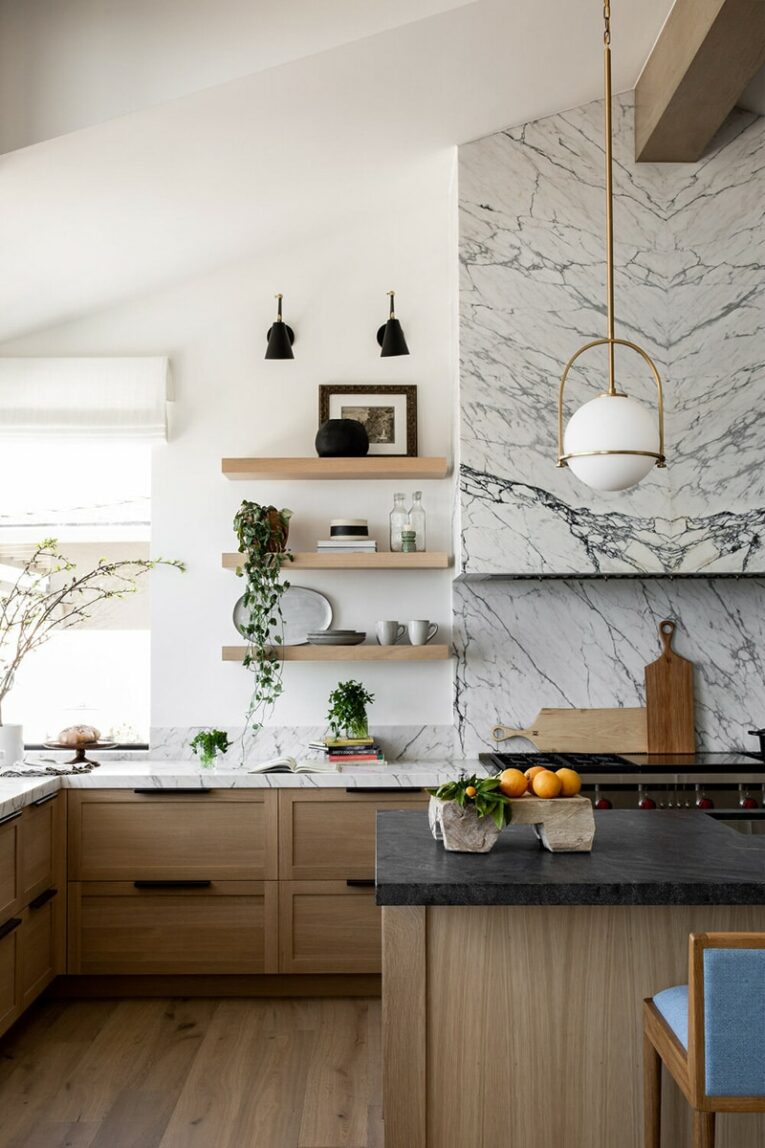 Open shelving and a marble hood in a kitchen.