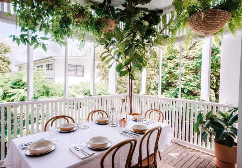 A deck with hanging plants and a table.