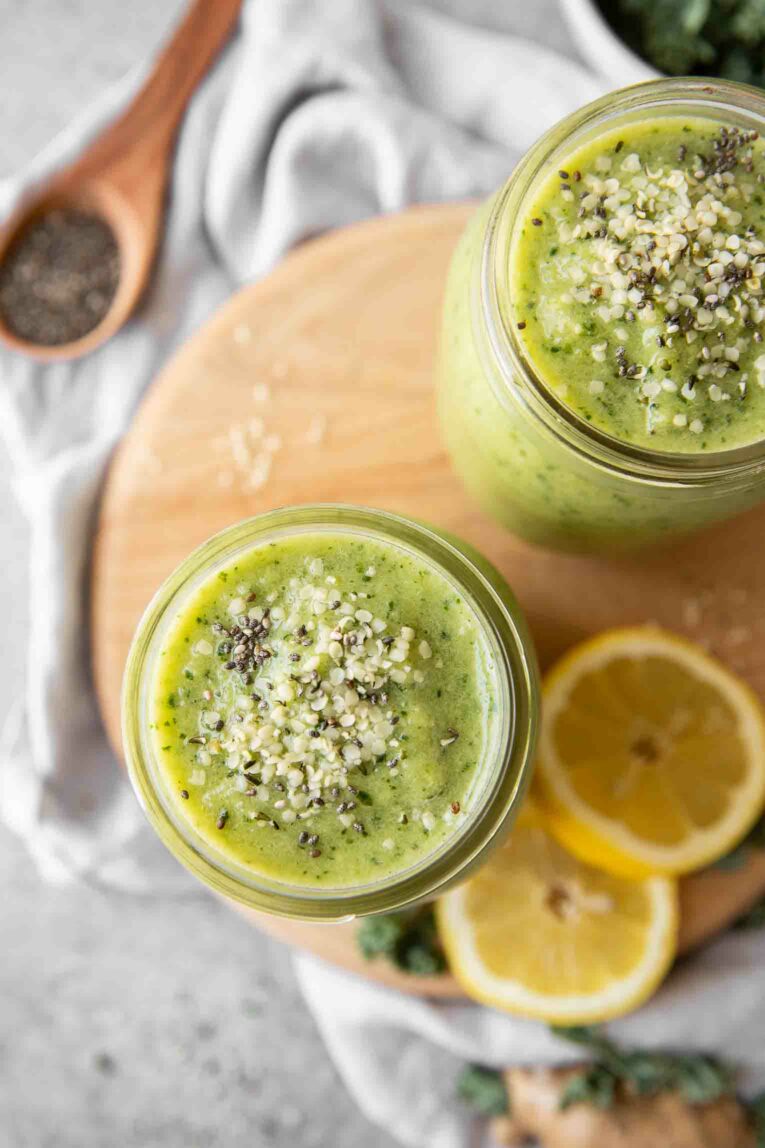 Top shot of two green smoothies in mason jars with toppings.