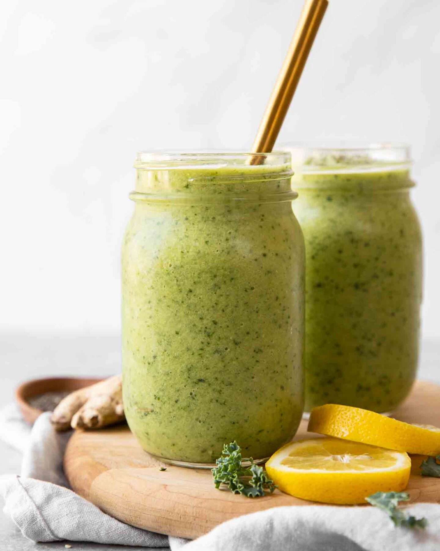 Across shot of Green Apple Detox Smoothie in a mason jar with a gold straw.