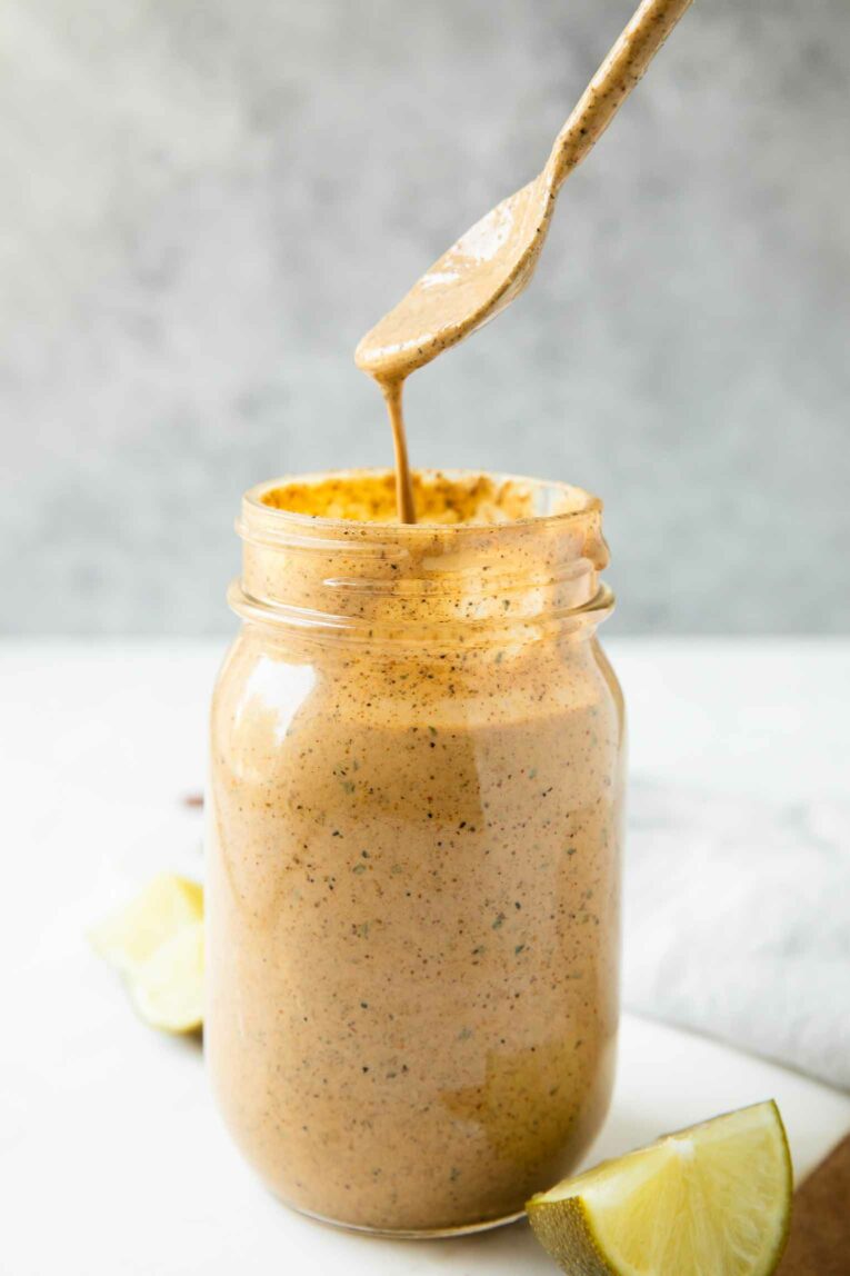Spoon pouring southwest salad dressing into a jar.